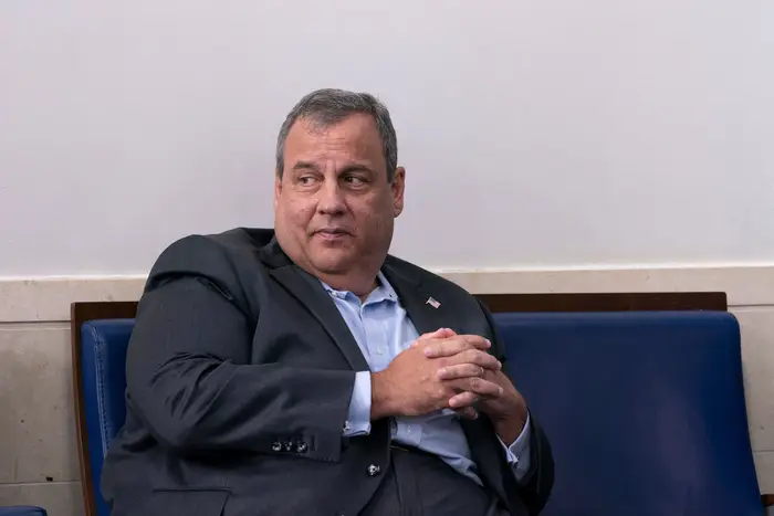 Chris Christie, in a suit without a tie, sits with his head turned